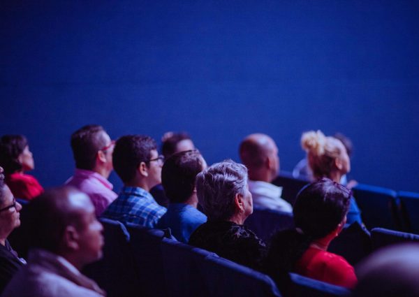 An attentive group of adults seated at an indoor conference, focusing on a presentation.